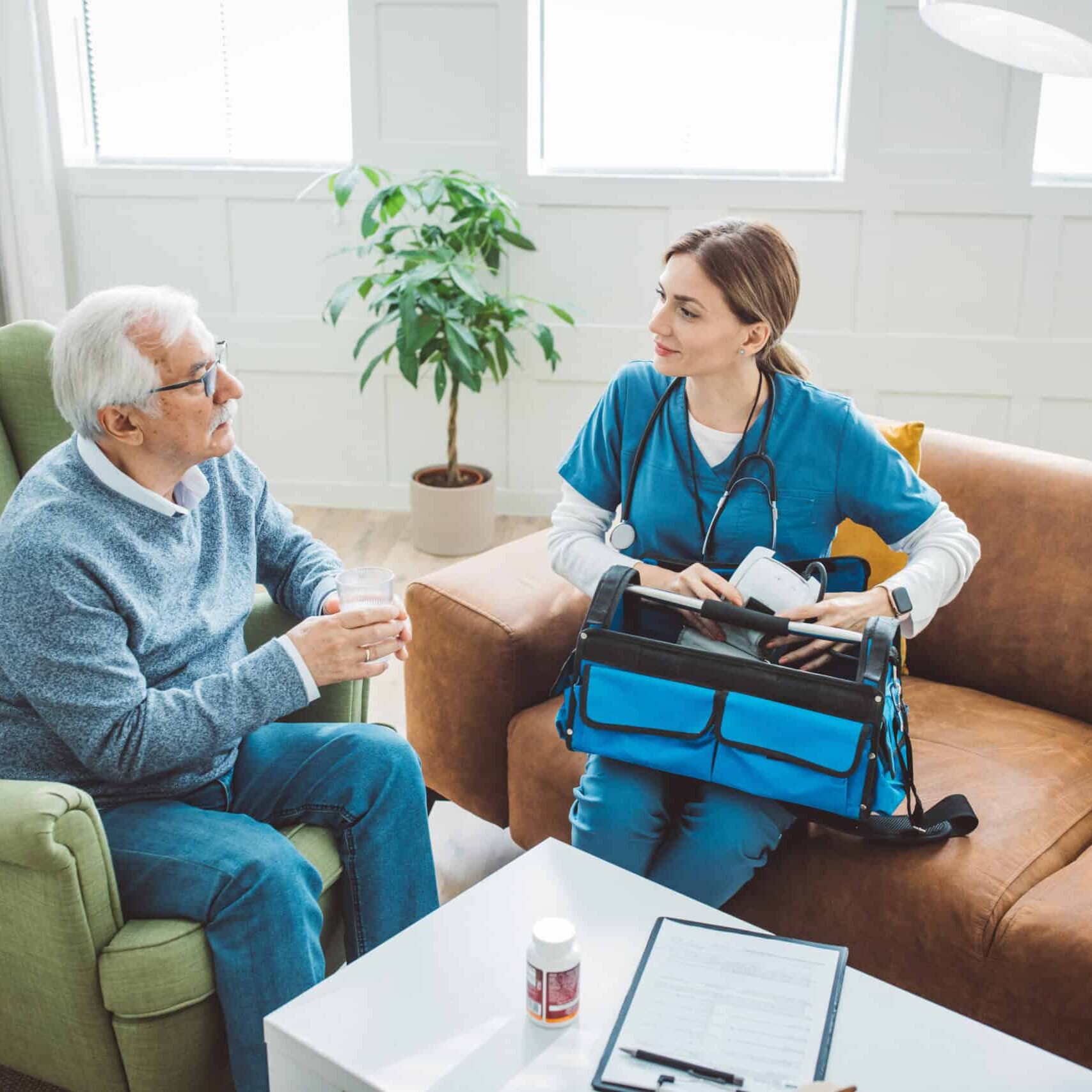 Nurse visiting mature patient at home. She is measuring blood pressure to patient at his living room.